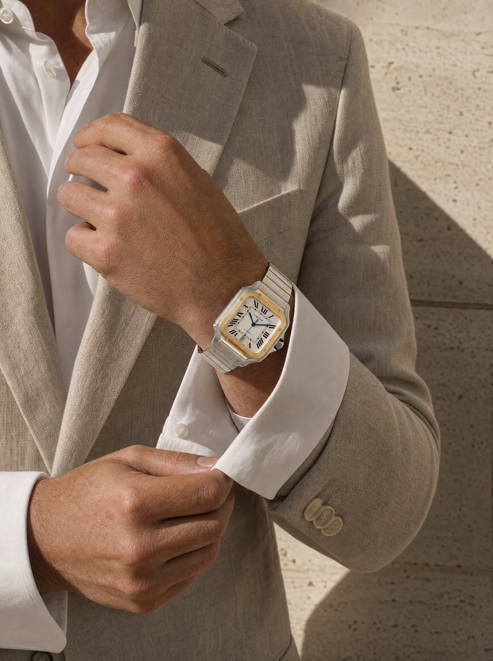 A yellow-gold Cartier Santos under a linen blazer cuff