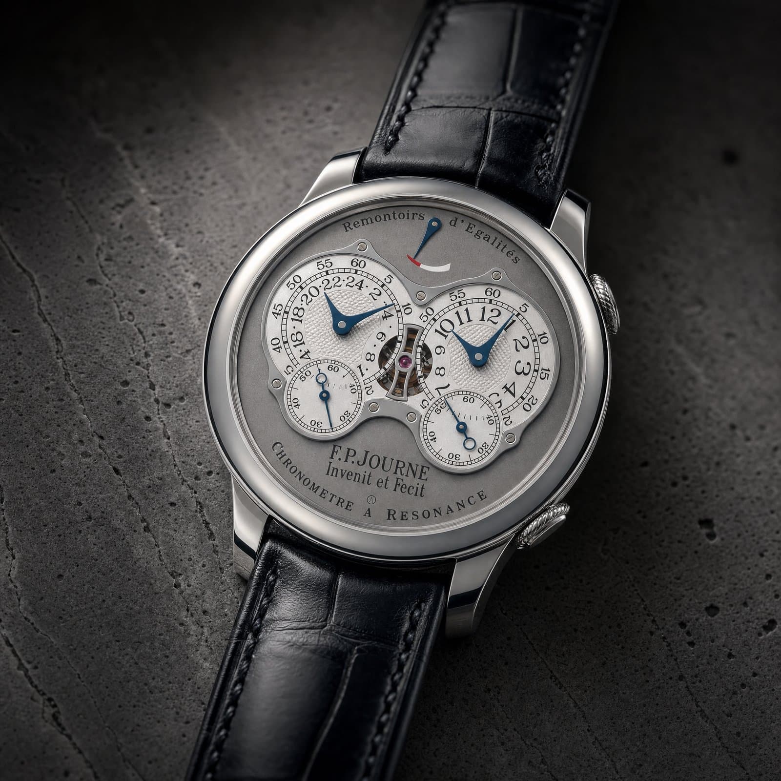 Macro of a grey-platinum Chronomètre dial on dark travertine
