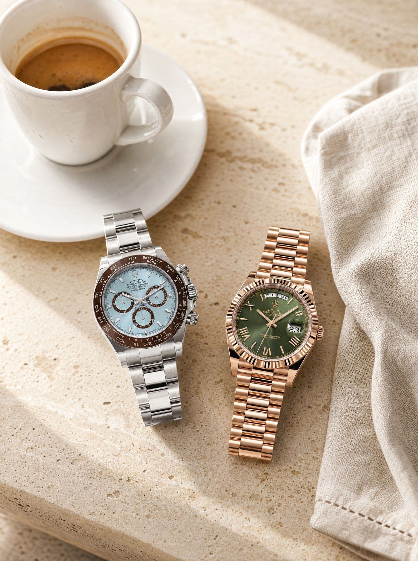 Two watches resting together on a travertine café table beside an espresso